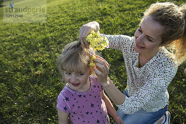 Austria  Tyrol  Walchsee  mother putting flowers into daughter's hair on an alpine meadow
