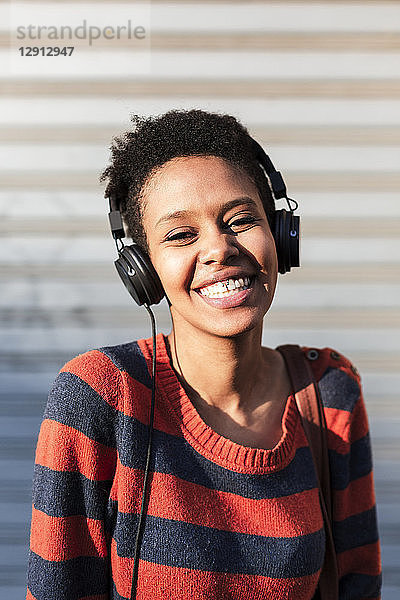 Portrait of laughing young woman listening music with headphones