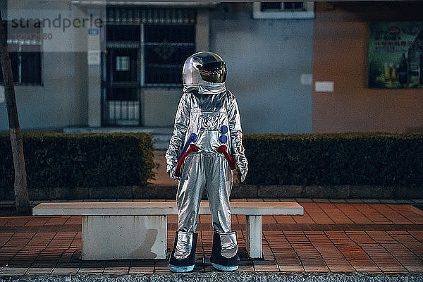 Spaceman standing at a bench in the city at night