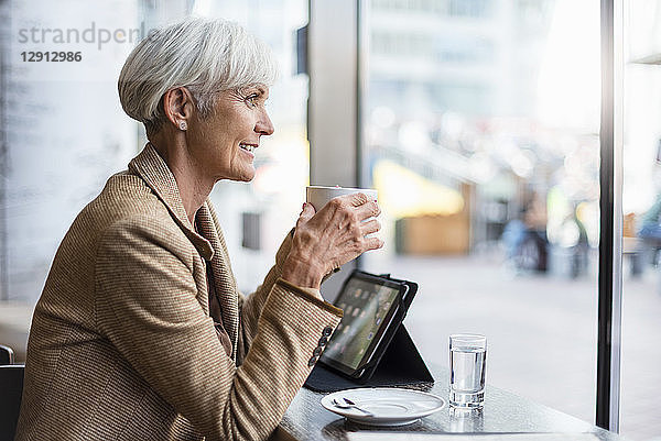 Smiling senior businesswoman with tablet in a cafe