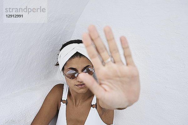 Young woman wearing white bikini top raising her hand