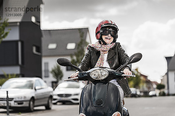 Active senior lady riding motor scooter in the city