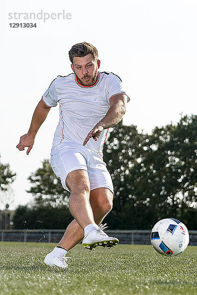 Young man kicking soccer ball
