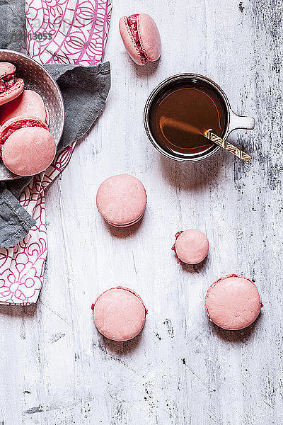 Pink macarons filled with raspberry buttercream and a cup of coffee