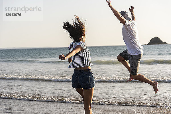 Young couple having fun on the beach  running and jumping at the sea