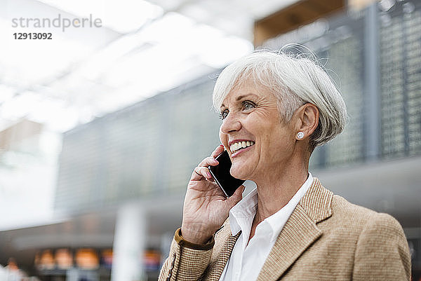 Smiling senior businesswoman on cell phone at the airport