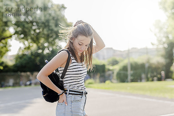 Portrait of smiling young woman with backpack outdoors in summer