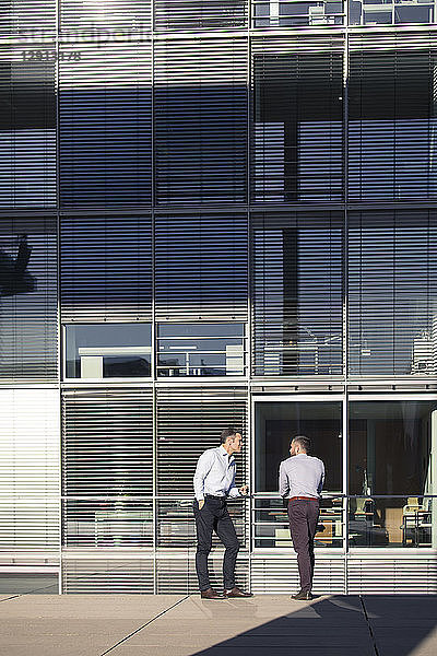 Two businessmen talking outside office building
