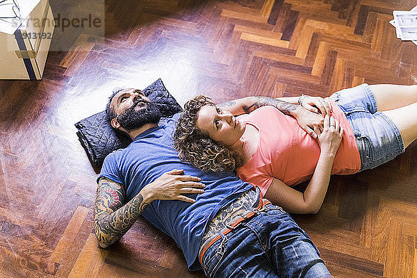 Daydreaming couple lying on the floor of new home