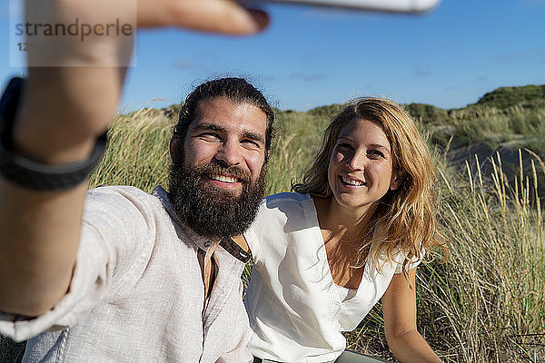 Happy couple taking smartphone selfie in nature