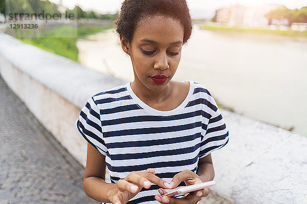 Young woman at the riverside using cell phone