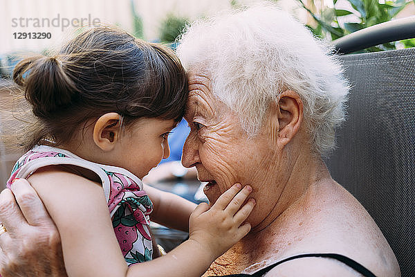 Grandmother face to face with her granddaughter on terrace