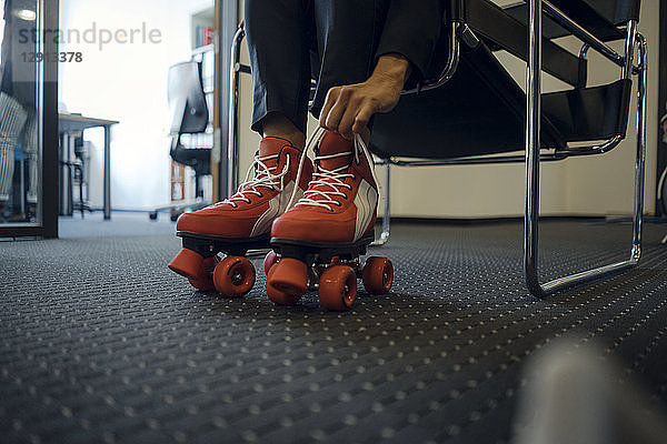 Mature businesswoman sitting in office  putting on roller skates