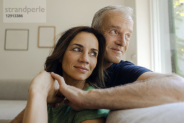 Smiling mature couple sitting on couch at home