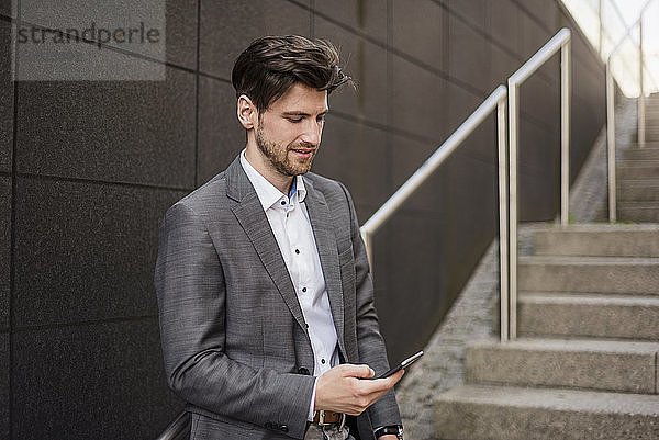 Businessman using cell phone on stairs