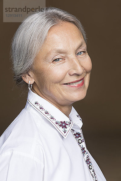 Portrait of smiling senior woman with grey hair wearing embroidered blouse