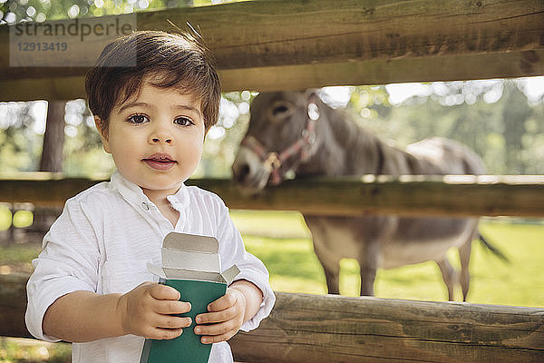 Portrait of toddler with box of animal food in wild park