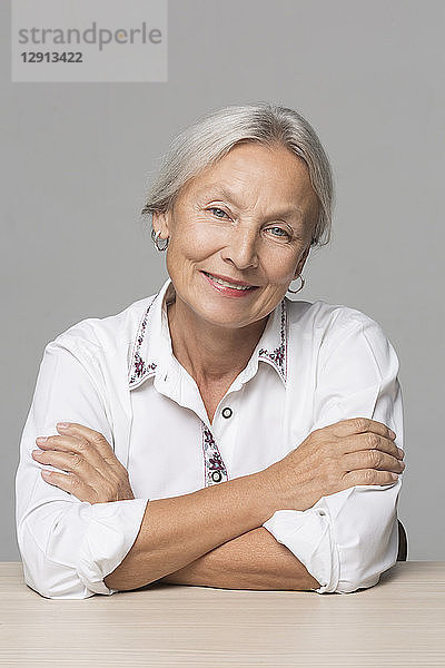 Portrait of senior woman with grey hair sitting at table