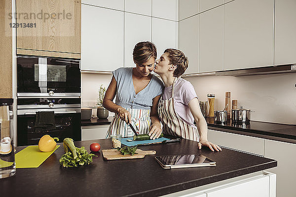Happy lesbian couple in kitchen cooking together