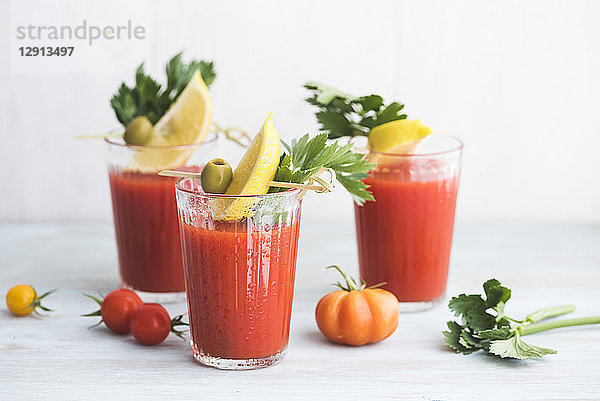 Glasses of fresh spicy tomato juice with cellery garnished with lemon slice  green olive and parsley