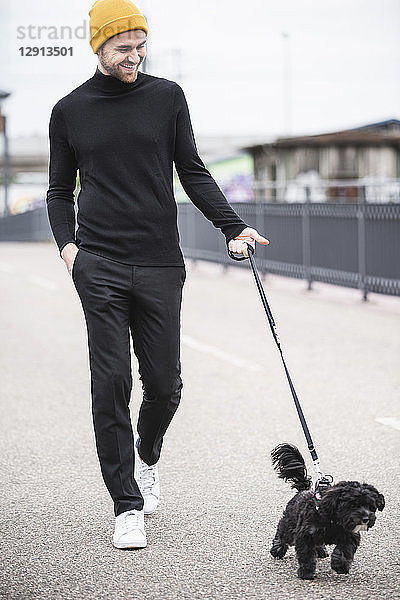 Fashionable young man walking with dog on a bridge