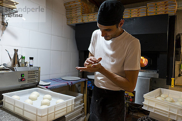 Pizza baker shaping dough in kitchen