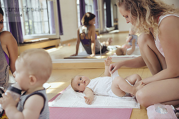 Mother changing diapers of baby in exercise room
