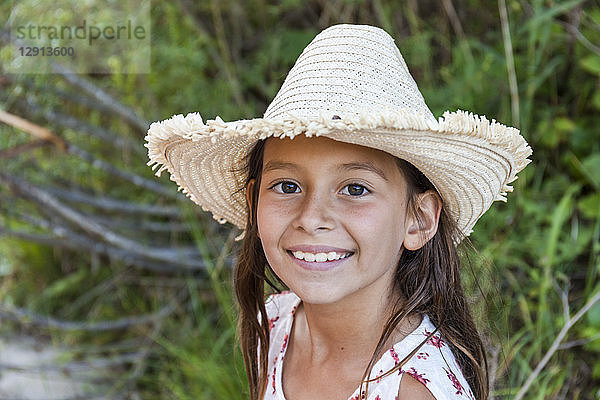 Portrait of smiling girl wearing straw hat outdoors