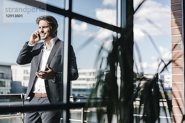Businessman making a phone call  standing on balcony
