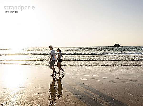 Young couple doing a romantic beach stroll at sunset