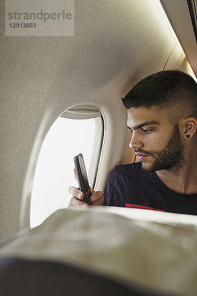 Young man in a plane with cell phone