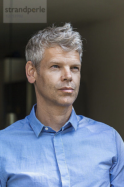 Portrait of pensive mature man with grey hair wearing blue skirt