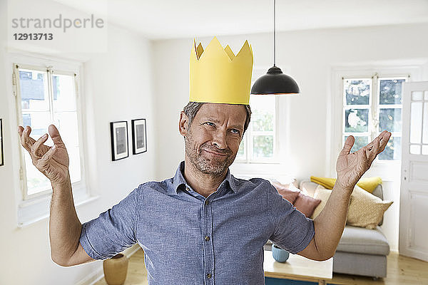 Mature man at home wearing paper crown  looking helpless
