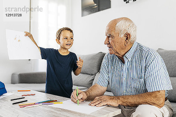 Grandfather and grandson drawing with coloured pencils in the living room