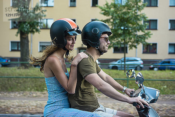 Couple riding motor scooter in the city
