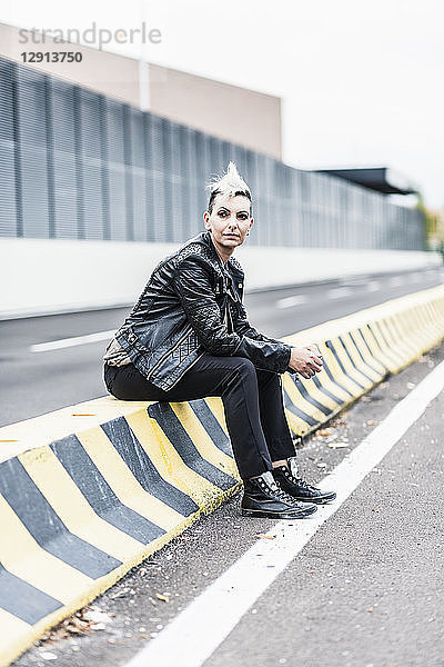 Punk woman sitting at the roadside looking around
