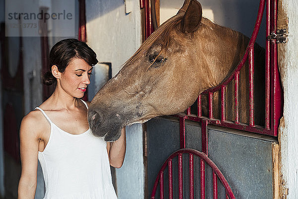 Portrait of woman stroking horse in stable