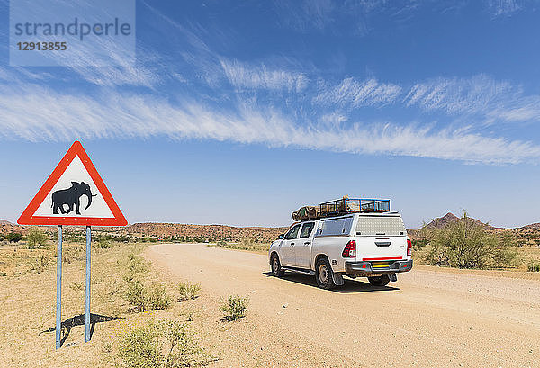 Namibia  Erongo Region  off-road vehicle on sand track  deer crossing sign with elephant
