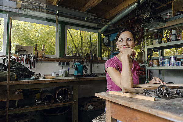 Smiling mature woman at workbench in her workshop