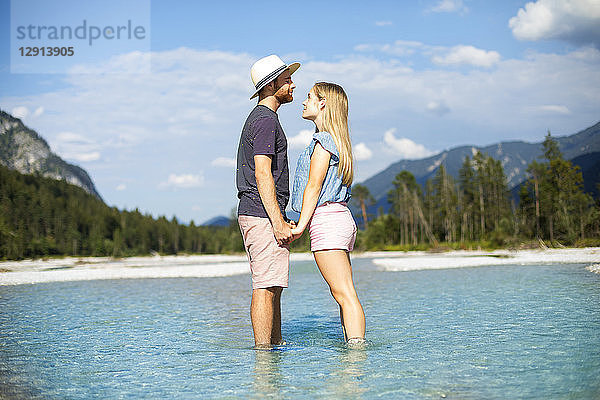 Young couple standing in water  holding hands