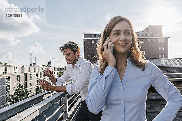 Business people standing on balcony  using smartphone