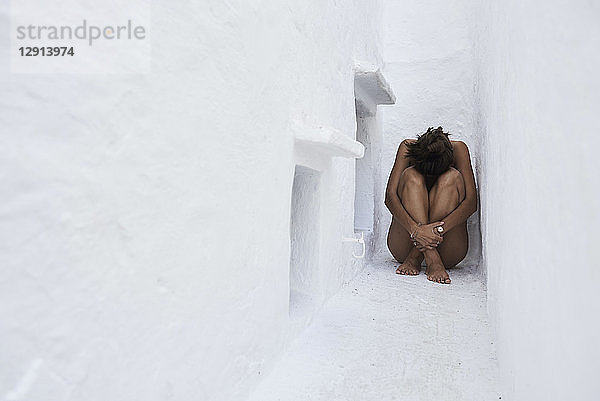 Young woman crouching in a wall niche