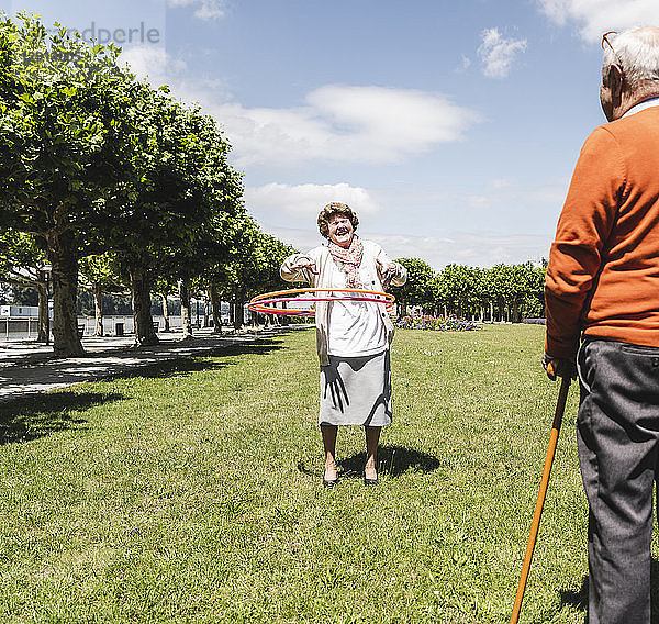 Senior watching elderly lady playing with a hoola hoop