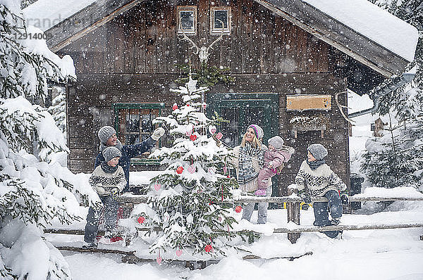 Austria  Altenmarkt-Zauchensee  family decorating Christmas tree at wooden house