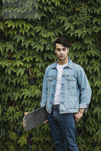 Portrait of young man carrying skateboard