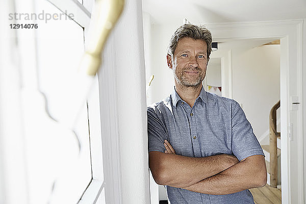 Mature man at home leaning in door frame