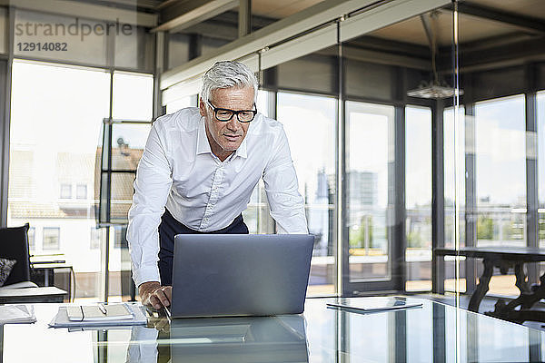 Businessman standing at desk  looking at laptop