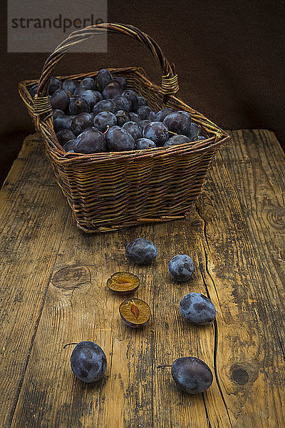 Wicker basket of organic plums  wooden table