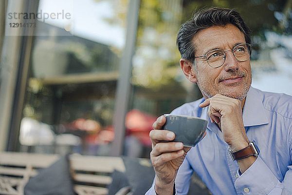 Mature businessman sitting in coffee shop  drinking coffee