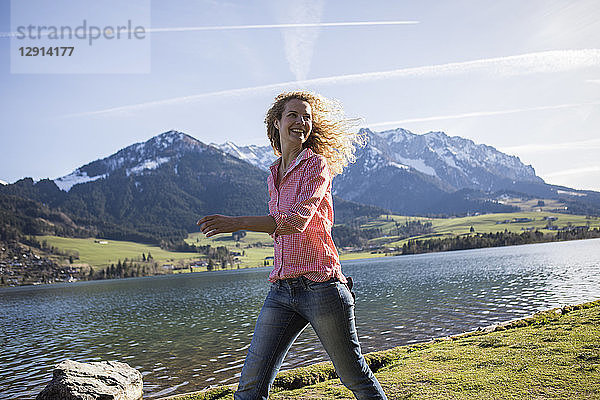 Austria  Tyrol  Walchsee  smiling woman walking at the lake